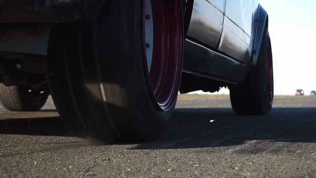 street drag racing. the wheels start with smoke on the asphalt in slow motion.