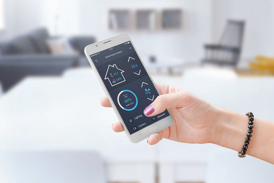 Woman hold smart phone and use smart home control app to monitoring home parameters.