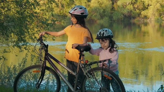 Children with a bicycle in nature. Sisters with a bicycle in the park.