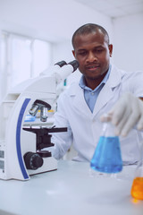 I love bioengineering. Smart experienced biologist working with his microscope and holding a tube