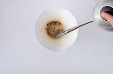 The stream of hot water from the kettle is poured on the filter  in the Chemex