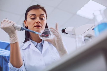 Testing blood. Inspired smart scientist conducting a blood test and wearing a uniform