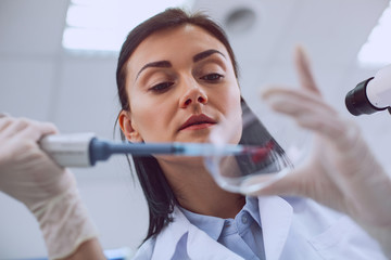 Naklejka premium Breakthrough. Skilled smart scientist conducting a blood test and wearing a uniform