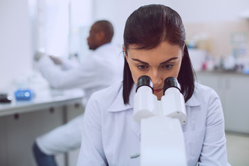 Women in science. Intelligent determined researcher working on her microscope while working in the...