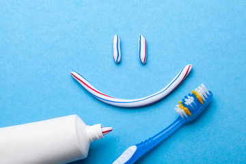 Tooth-paste in the form of a face with a smile. Tube of toothpaste and toothbrush on a blue...