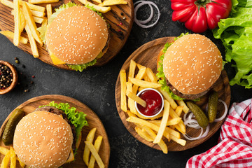 Tasty burgers, cheeseburgers, french fries, salad and red plaid kitchen textile, table top view....