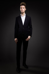 Obraz na płótnie Canvas Portrait of handsome man in black suit on a black background
