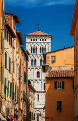 View of Lucca historic center with Saint Michael in Foro medieval bell tower seen from city narrow street