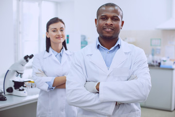 We are happy. Inspired successful researchers wearing uniforms and standing in the lab