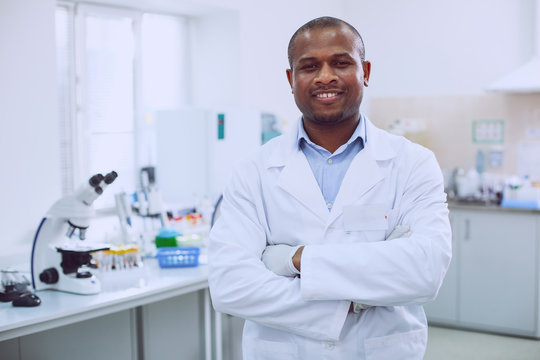 I feel great. Happy successful researcher wearing a uniform and standing in the lab