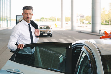 Smiling mature businessman getting in taxi outside