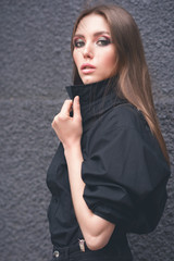 Beautiful girl in black clothes oversize with suspenders. Dark background. Toned image.