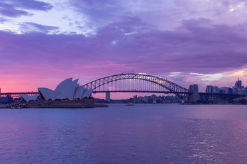 operahuis en havenbrug in Sydney bij zonwolken in schemertijd, het zijn iconische oriëntatiepunten van Australië. Australië