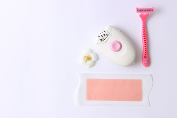 a set of different tools for hair removal on a light background. Removal of unwanted hair. a modern epilator, a razor, wax strips. minimalism, top view, flatlay 