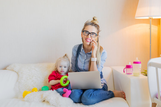Happy business woman with toddler working on computer