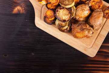 Close up top view of grilled chicken on a wooden board next to grilled vegetables