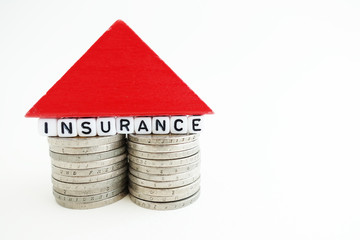 House insurance concept with small house from coins and wooden piece on white background
