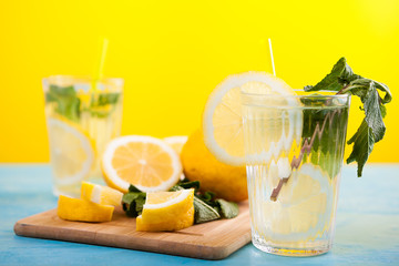 Fresh homemade lemonade in two glasses next to organic lemons on a wooden board