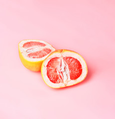 Two Red Grapefruit slices on pastel pink background. Minimal healthy fresh fruit concept. Fashion Top View.