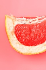 Red Grapefruit piece on pastel pink background. Minimal healthy fresh fruit concept. Grapefruit succulent pulp.