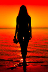 Black silhouette of a beautiful woman in the water by the sea at sunset
