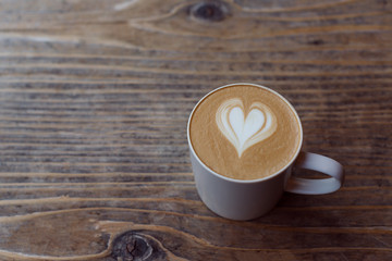 Cup of cappuccino coffee with heart shape latte art on the wood table