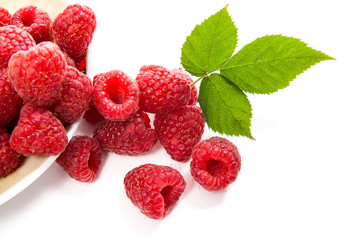 Small plate with ripe raspberries and green leaf isolated on white background.