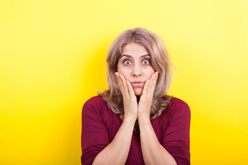 Beautiful blonde woman surprised on yellow background in studio photo