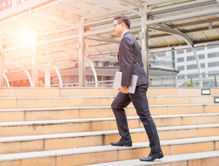 Business man with his laptop going up the stairs  in a rush hour to work . Hurry time.