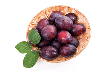 Yellow wooden basket with ripe plums isolated on a white background..