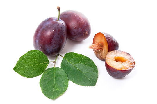 Group of whole and half of ripe plums with leaf isolated on a white background..