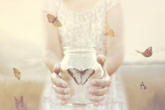 woman gives freedom to some butterflies enclosed in a glass vase