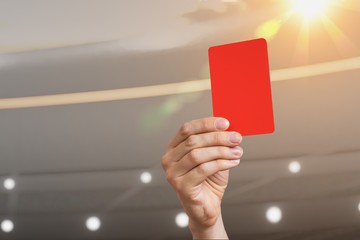 Close-up view on referee hand showing red card in soccer stadium.