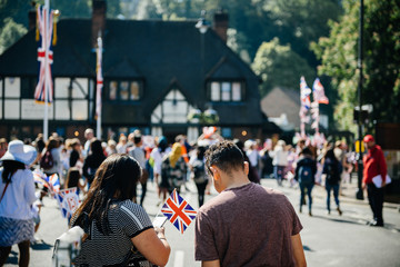 Unrecognizable couple with flags using phone on Windsor street for royal wedding marriage celebration of Prince Harry, Duke of Sussex and the Duchess of Sussex Meghan Markle 