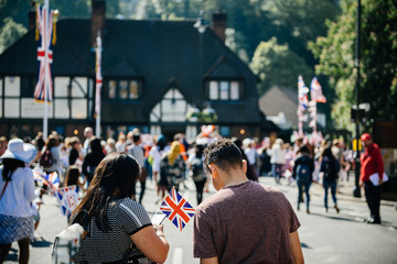 Unrecognizable couple with flags using phone on Windsor street for royal wedding marriage...