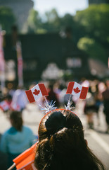 Rear view of funny woman with Canada flag antennas on head walking on street in Windsor for royal...