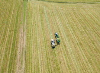 Aerial view of tractor and harvester on agricultural field on warm summer day in Switzerland