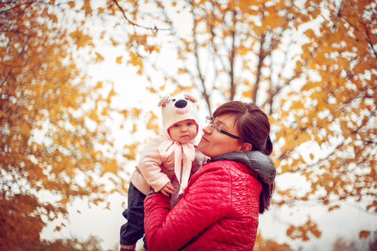 Mom with a child playing in autumn park.