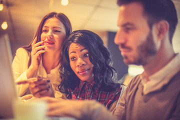 Tree young colleagues working together at cafe on laptop.