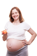 Beautiful preganant woman holding a red apple in her hands isolated over white background