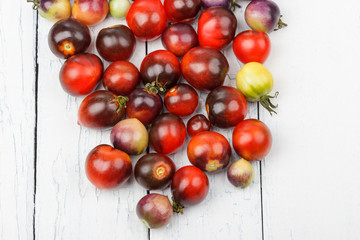 Different tomatoes on the white wooden background