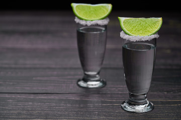 Two shot silver  tequila a black wooden background