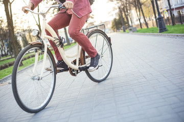 Naklejka premium A man in red jeans and sneakers on a beige bike on the mall
