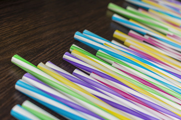Colorful paper straws on a wooden background. Accessories for events and parties.