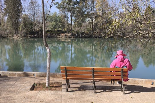Isolated woman on the bench dressed in fuchsia (Lijiang, Yunnan, China)