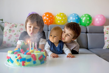 Cute children, boy brothers, celebrating birthday with colorful cake, candles, balloons