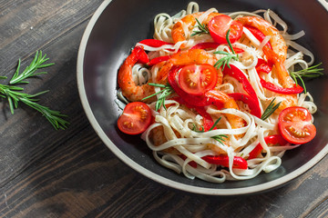 Fried shrimp with pasta, paprika and rosemary in a blackplate