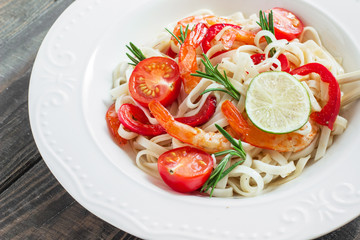 Fried shrimp with Udon noodles, paprika and rosemary in a white plate