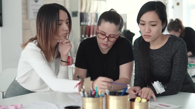 group of business woman working on a startup of a small atelier. several fashion designers discuss plans and ideas of work