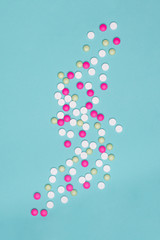 Assortment of various colourful pills isolated on blue pastel coloured background. Medication and prescription pills flat lay background.